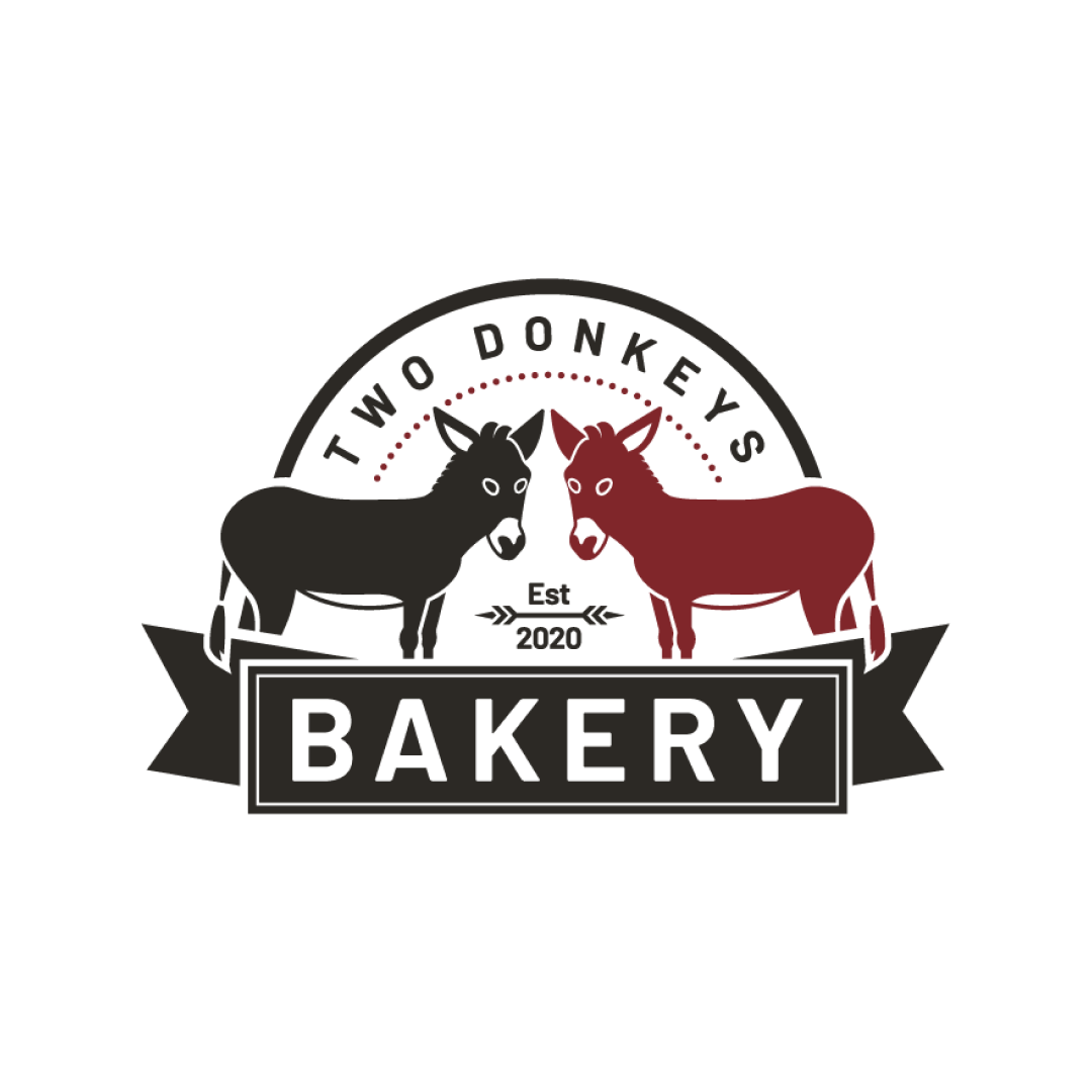 Two Donkeys Bakery logo featuring two donkeys, one gray and one red, facing each other above a banner with the word 'Bakery,' framed by a circular emblem with 'Two Donkeys' and 'Est. 2020.'